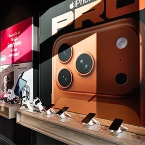 iPhone Pro Werbeposter im Elektronikmarkt, Smartphones auf Holztheke