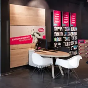 Beratungsbereich im Elektronikmarkt mit Tisch, Stühlen und Zubehörregal