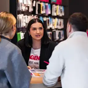 Beratungsgespräch im Handyshop: Verkäuferin erklärt Smartphone-Zubehör am Tisch